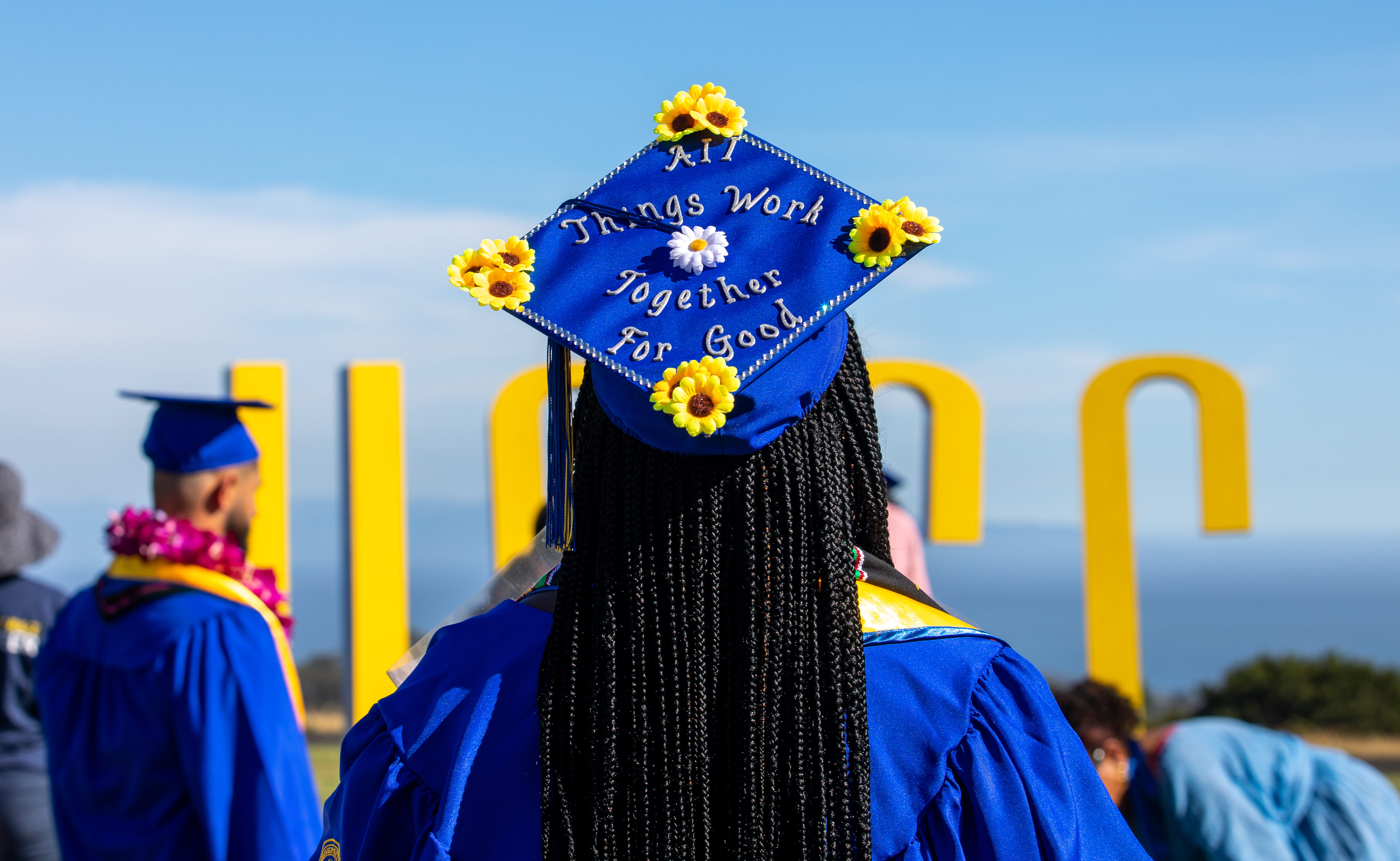 View of student wearing graduation cap from behind with UCSC logo in background